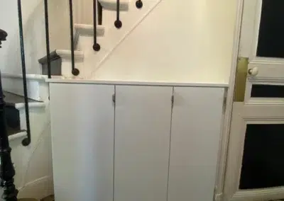 Placard blanc sous escalier avec carrelage géométrique.