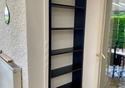 Étagère noire encastrée dans un coin lumineux avec miroir.