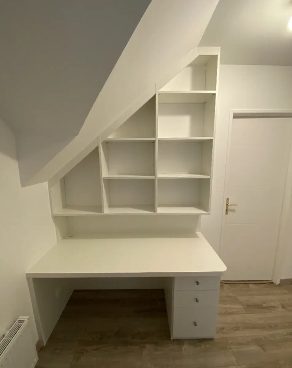Bureau blanc avec étagères intégrées sous pente.