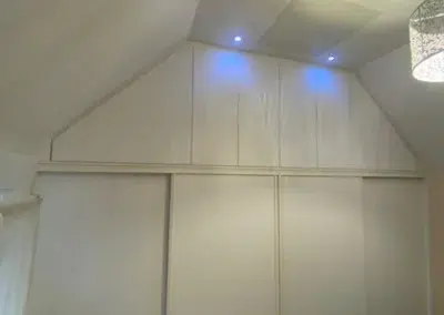 Placard encastré sous plafond incliné avec éclairage LED.