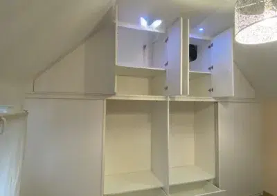 Placards blancs avec tiroirs sous plafond incliné
